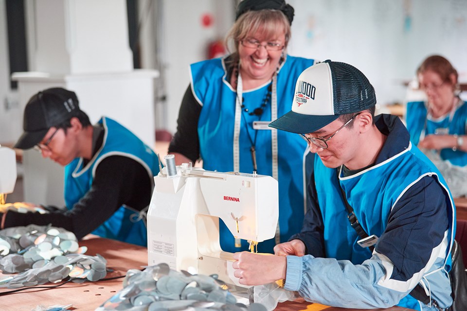 Volunteer teaching sewing to public
